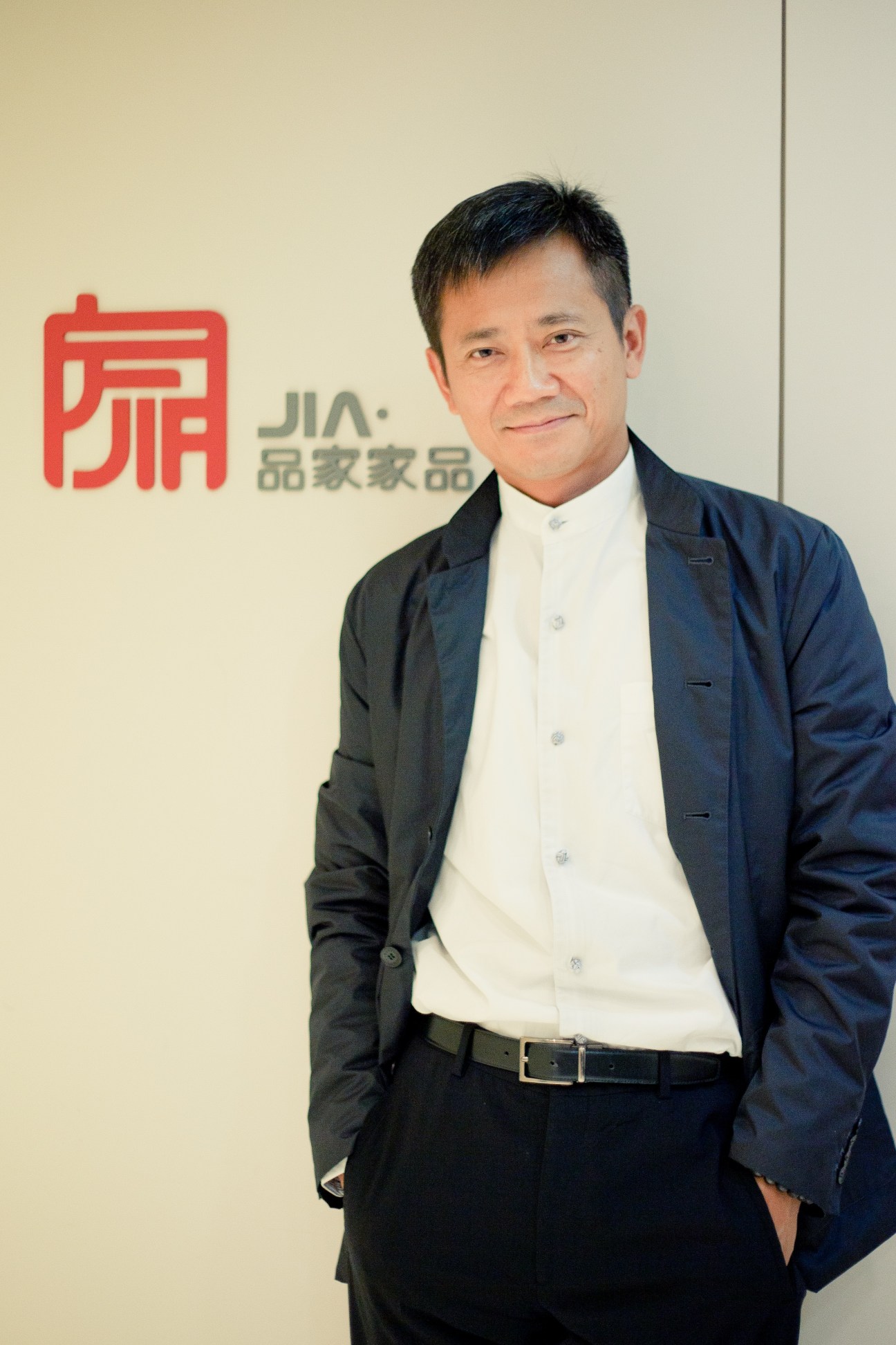 Christopher Lin, founder and president of Jia Inc, standing in front of the company's red logo