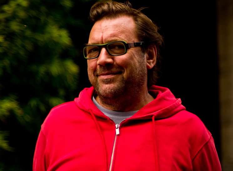 Portrait of Michael Marcy, owner of Michael Marcy furniture shop, wearing glasses and a red jacket.