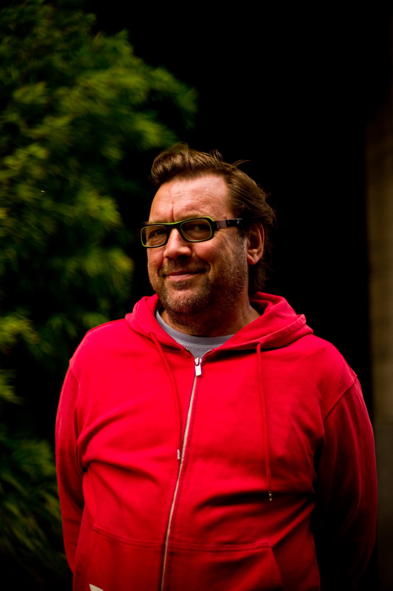 Portrait of Michael Marcy, owner of Michael Marcy furniture shop, wearing glasses and a red jacket.