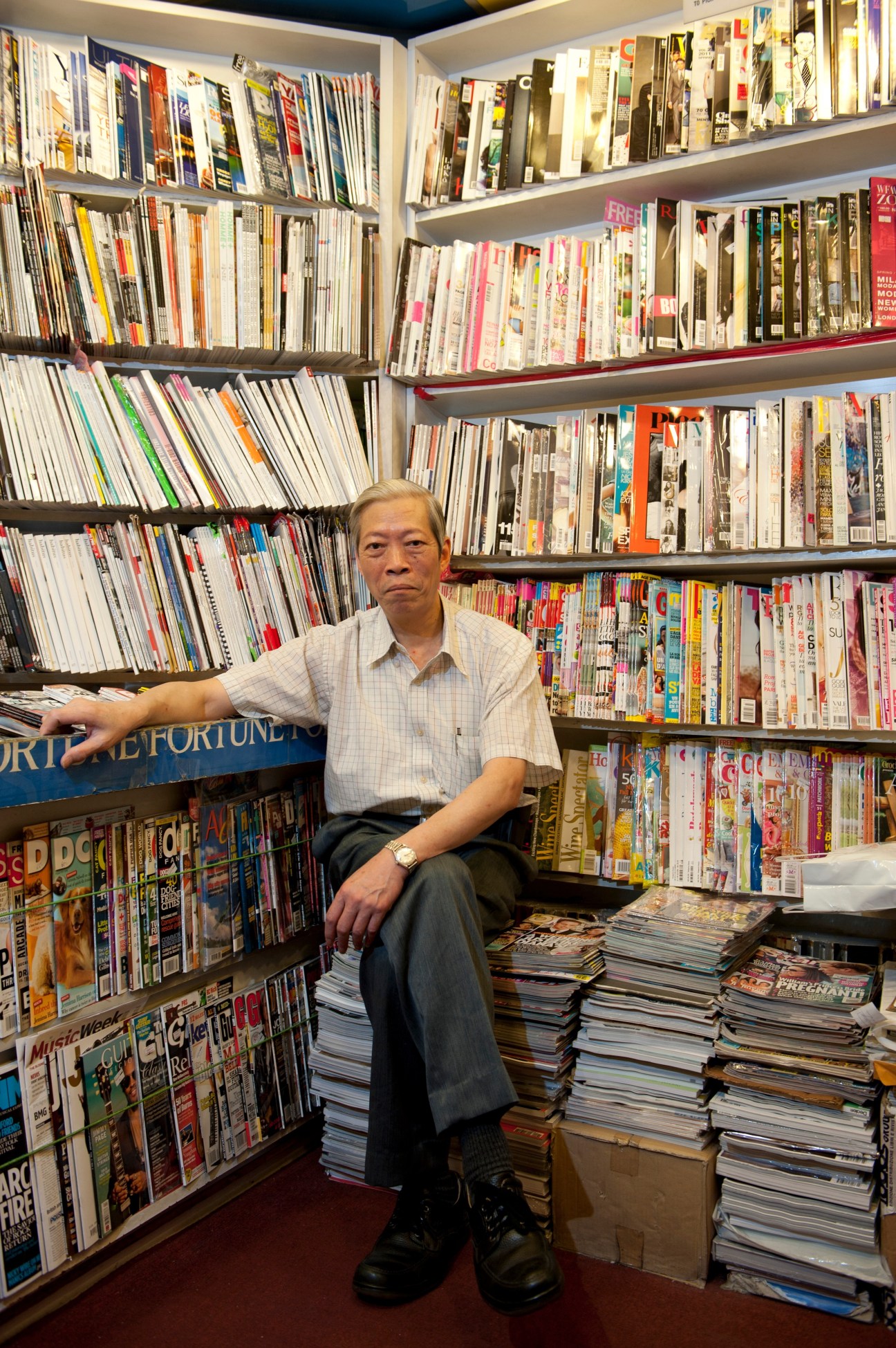 Wong Chung Pak, owner of Chaip Coin magazine shop in Hong Kong, sits among shelves of international magazines in his small newsstand.
