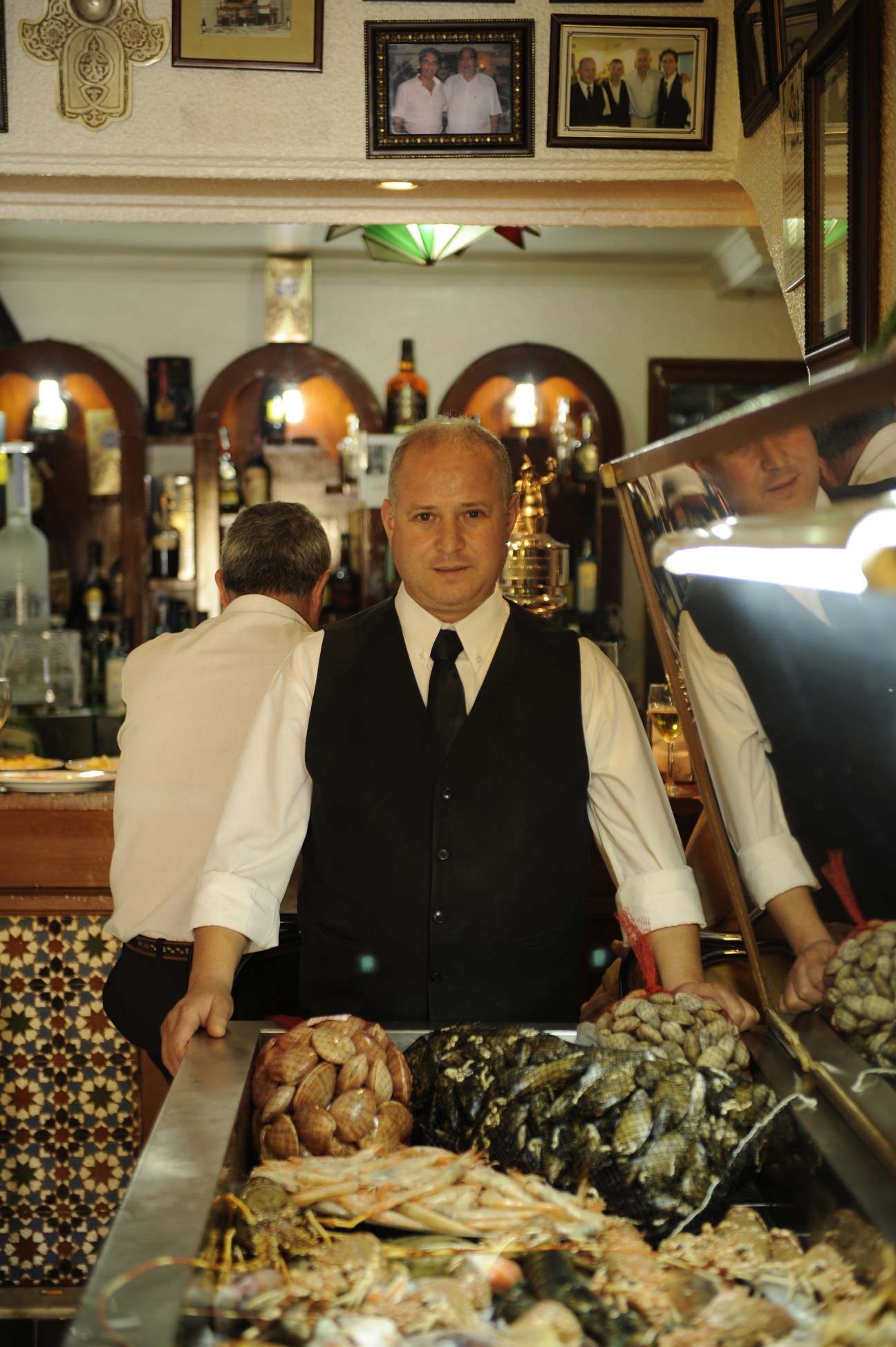 Chabouri Najib, maître d' at Casa Juanito seafood restaurant, standing behind the counter in Melilla.