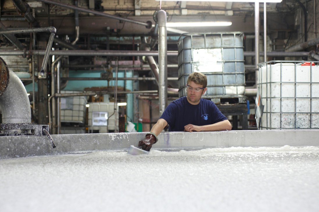 Worker checks wet pulp from blending chamber at James Cropper paper mill.