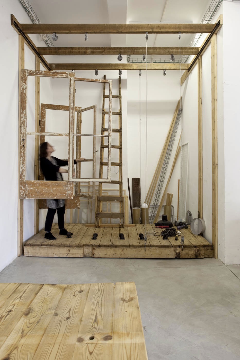 Artist Yael Toren works in a minimalist studio space with wooden beams and recycled materials.