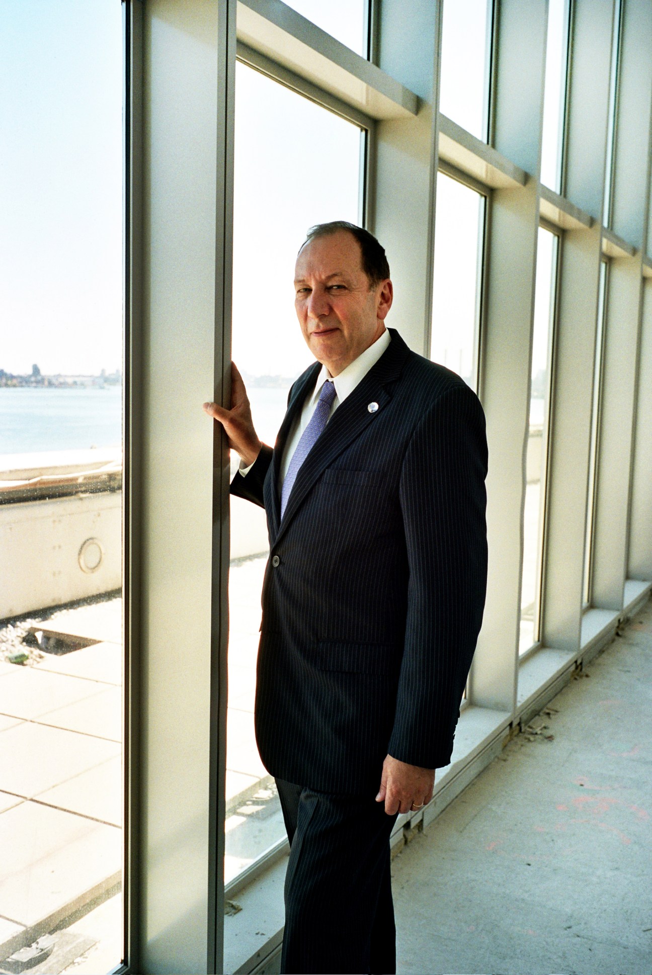 Michael Adlerstein stands by floor-to-ceiling windows at UN Headquarters overlooking the East River.