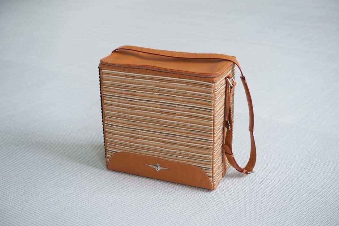 Brown leather bag with woven horizontal stripe pattern and shoulder strap.