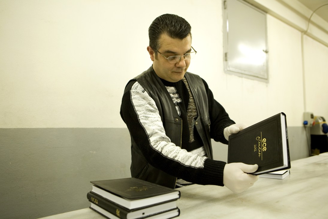 Man in glasses examining a black Ece diary during quality control inspection.
