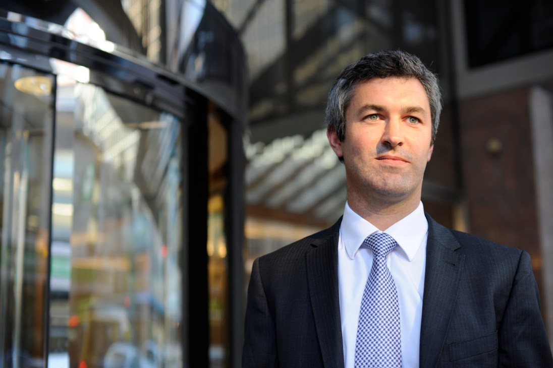 Hugh Stevens, head of BNP Paribas Security Services NZ, in business attire outside a modern building.