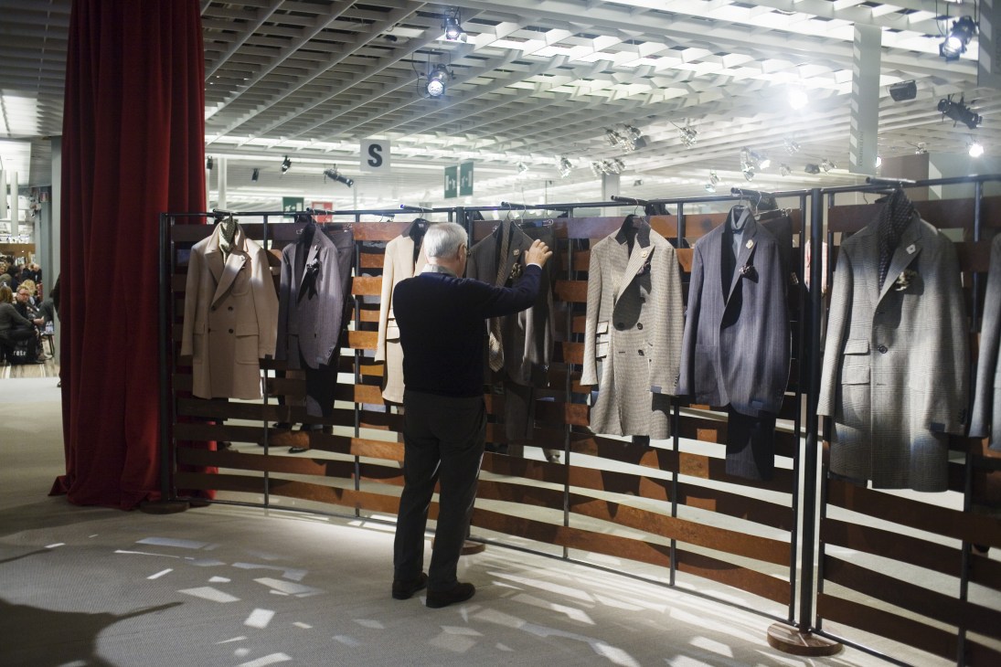 A man examines Lardini coats and jackets displayed on a rail at Pitti Uomo trade show.
