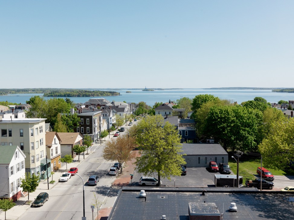 Aerial view of Portland's Munjoy Hill neighborhood with historic buildings, streets, and Casco Bay in the distance.