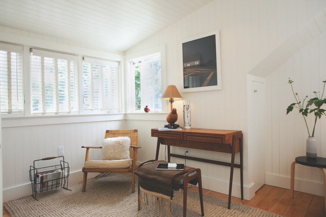 Master bedroom with wooden mid-century furniture, including Edith Heath's wicker-backed chair by the window.