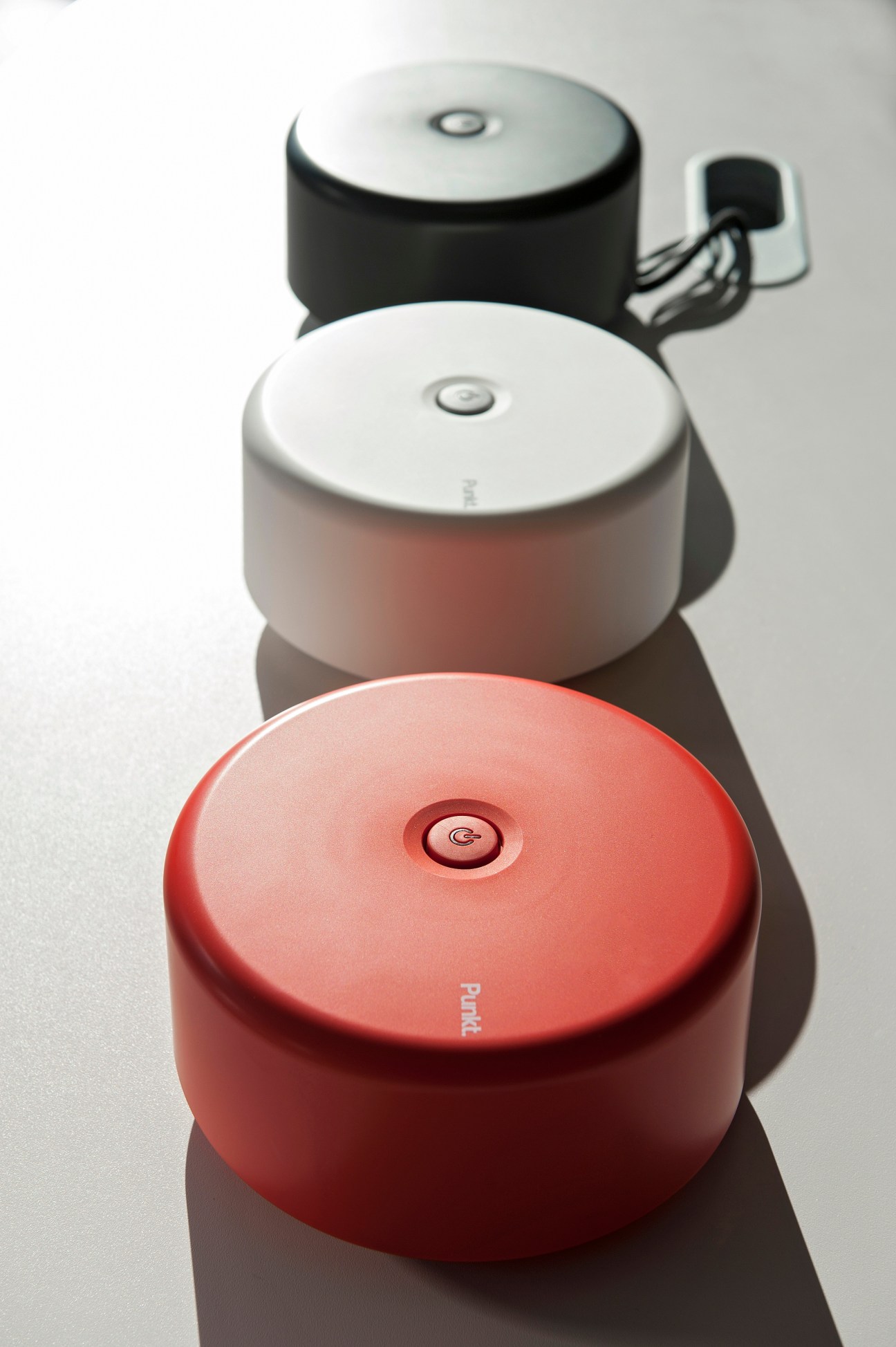 Three Punkt electronic devices in red, white and black colors arranged vertically, showcasing minimalist design.