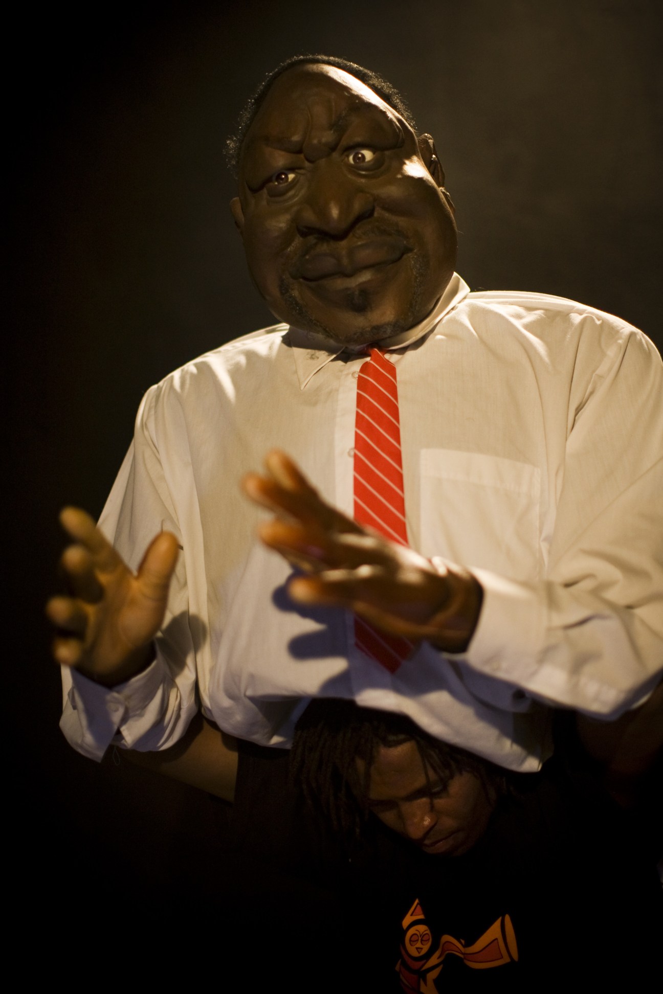 Raila Odinga puppet wearing white shirt and red striped tie, with exaggerated facial features and gesturing hands.