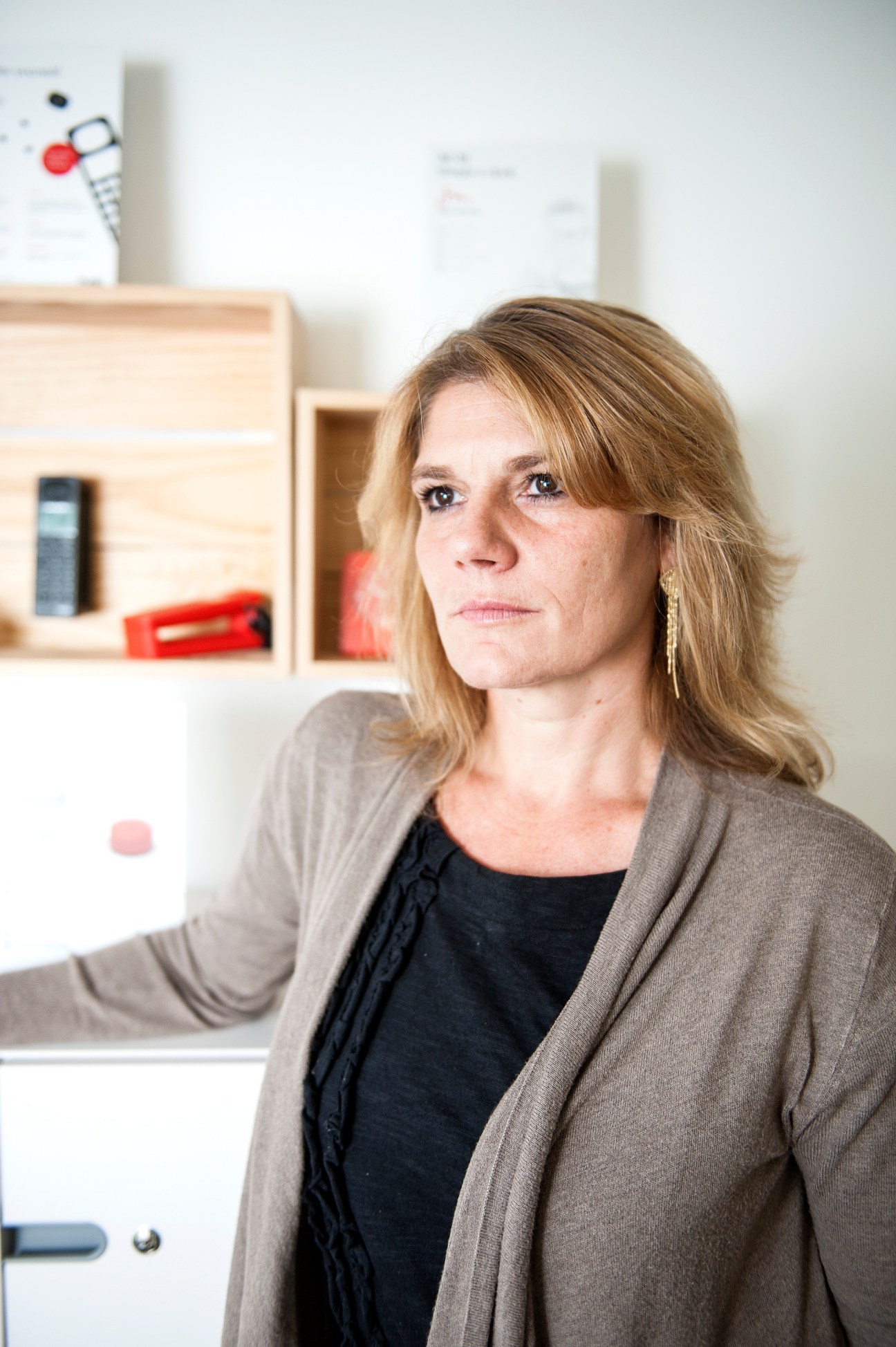 Rafaella Cardarelli, CEO of Swiss electronics brand Punkt, poses in an office with wooden shelving and red accents behind her.