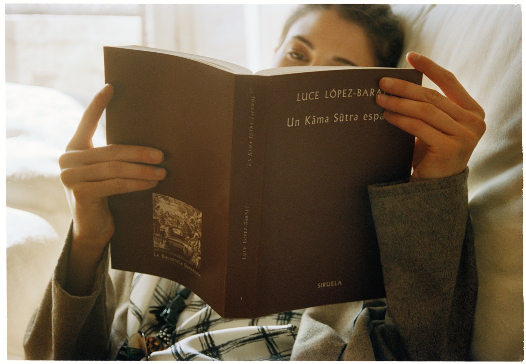 Model Carina Pichler reading a book by Luce López-Baralt while relaxing indoors.