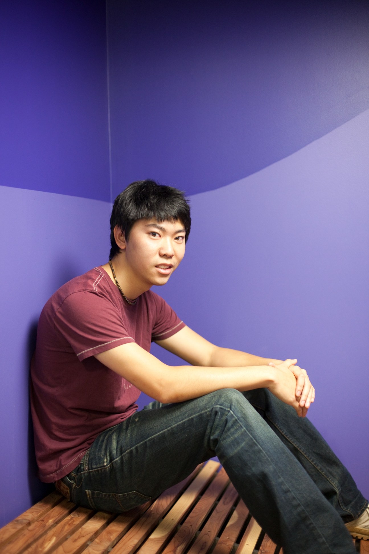 Young male student William Dong sitting against a purple wall at Stanford's d.school