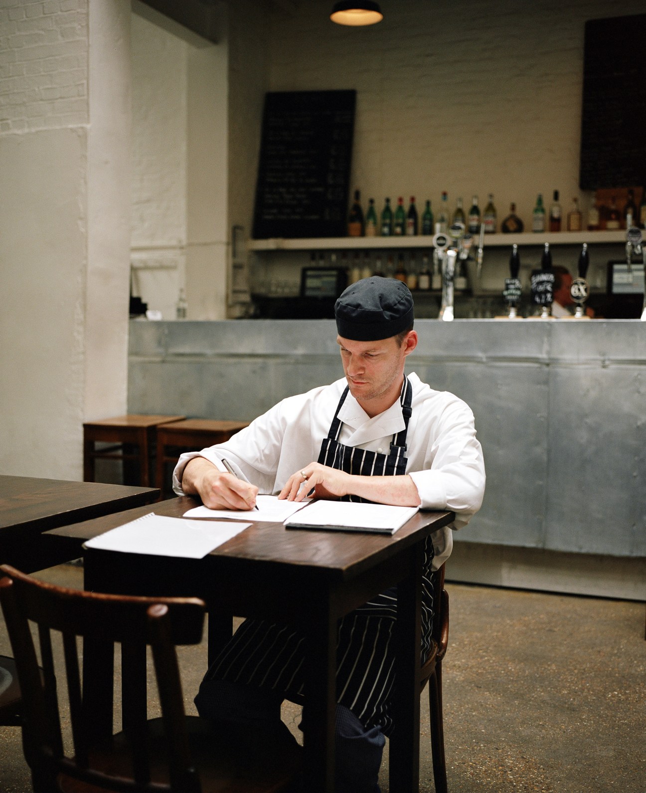 Head chef Chris Gillard writes at a table in St John restaurant's dining room.