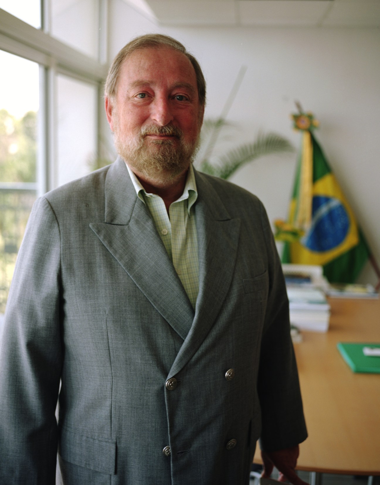 Brazilian ambassador Igor Kipman stands in his embassy office with the Brazilian flag visible in the background.