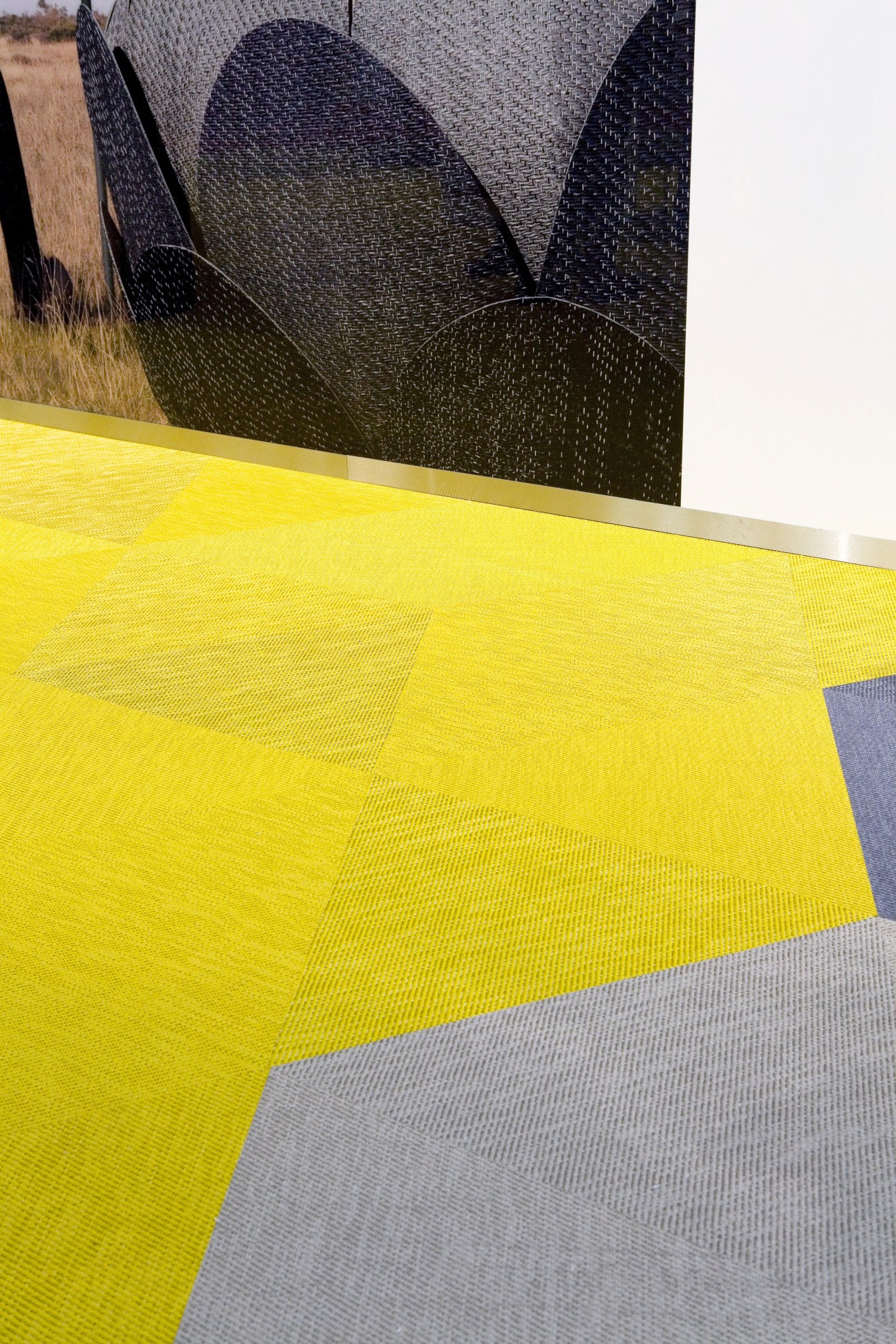 Bolon's Botanic vinyl carpet in bright yellow displayed alongside dark patterned flooring samples.