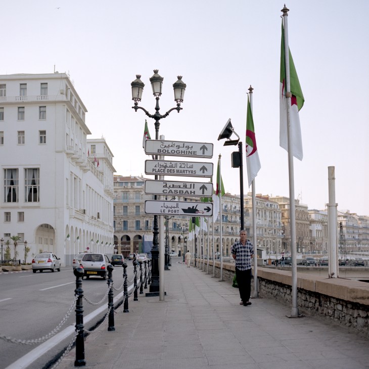 Street signs in Arabic and French directing to Bologhine, Place des Martyrs, Casbah and Le Port on Algiers' Corniche waterfront.