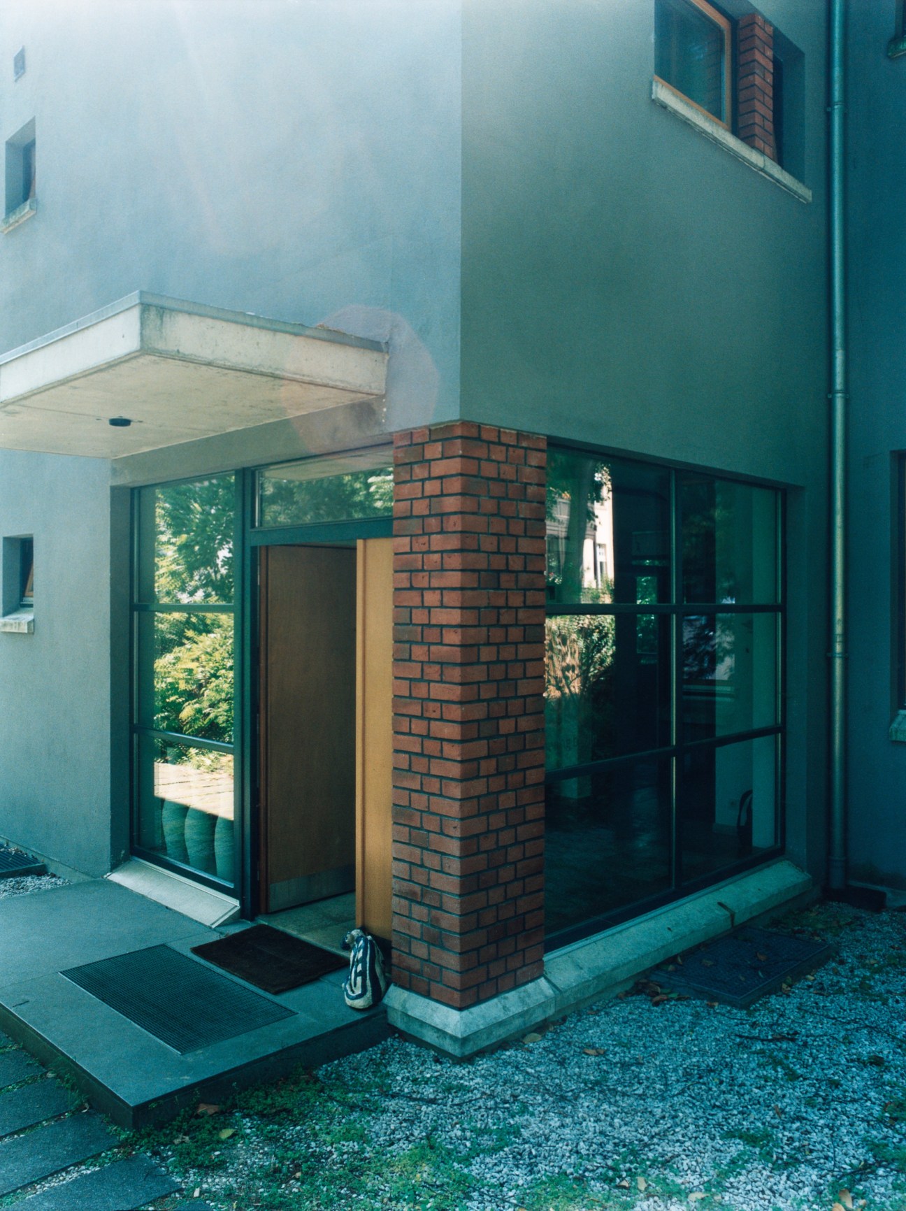 Modern entrance to Hering Berlin porcelain showroom with brick chimney and green-framed windows.