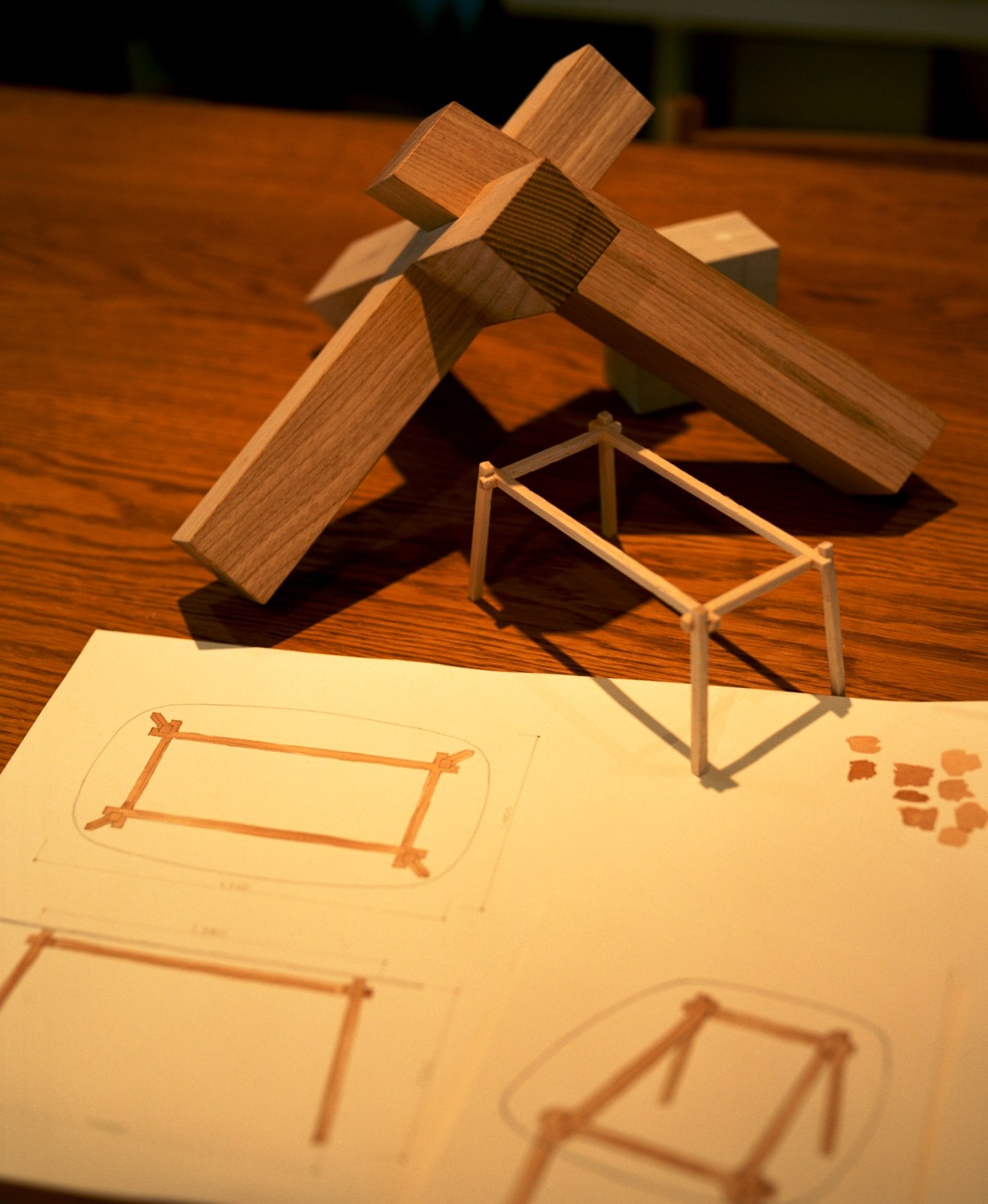 Wooden furniture models and sketches for a table design, displayed on a work surface.
