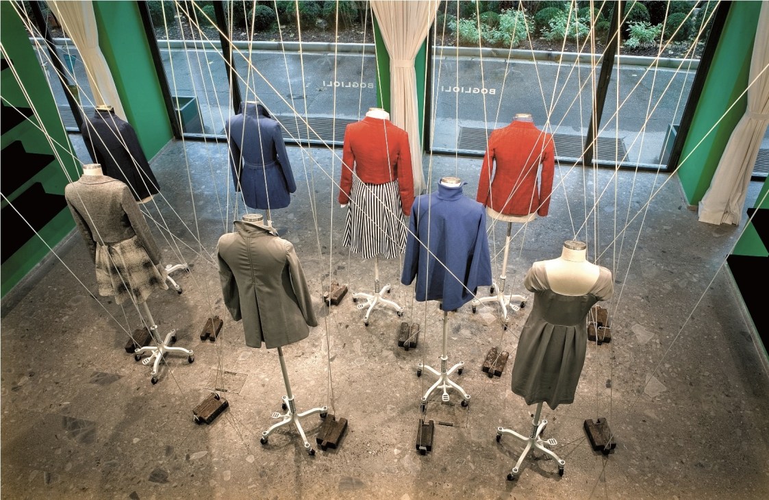Boglioli clothing displayed on mannequins in a retail showroom with green walls and large windows.