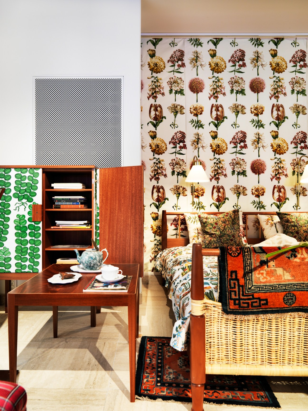 Bedroom display featuring wooden furniture, floral wallpaper, patterned textiles, and decorative objects at Svenskt Tenn store.