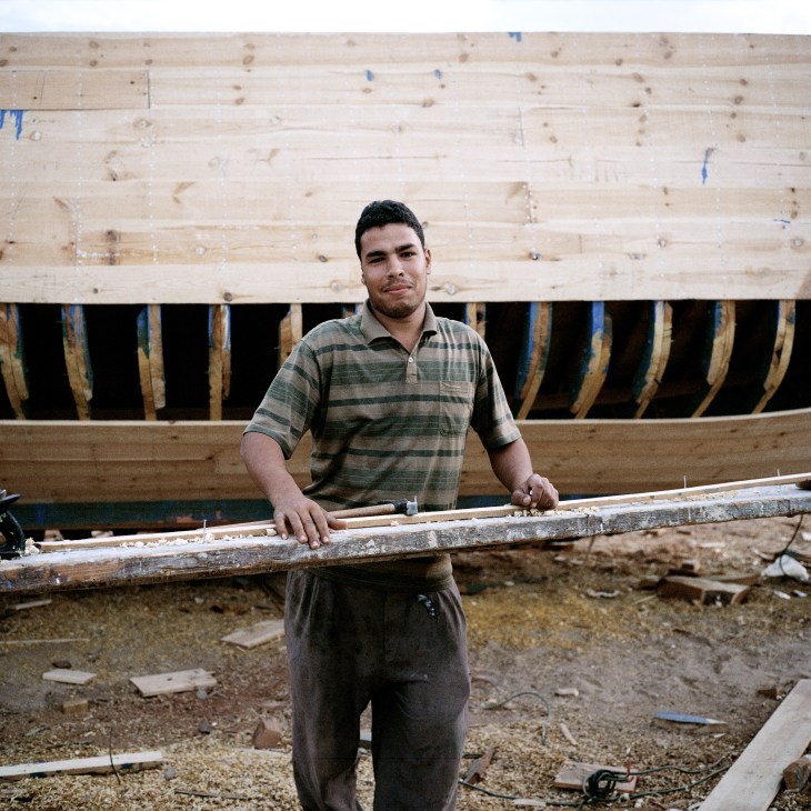 Worker holding wooden plank at shipbuilding yard along Suez Canal, Egypt.