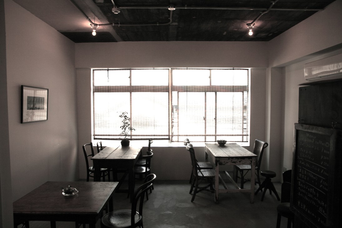 Interior of Starnet Osaka store with wooden tables, black chairs, and large windows overlooking the street.