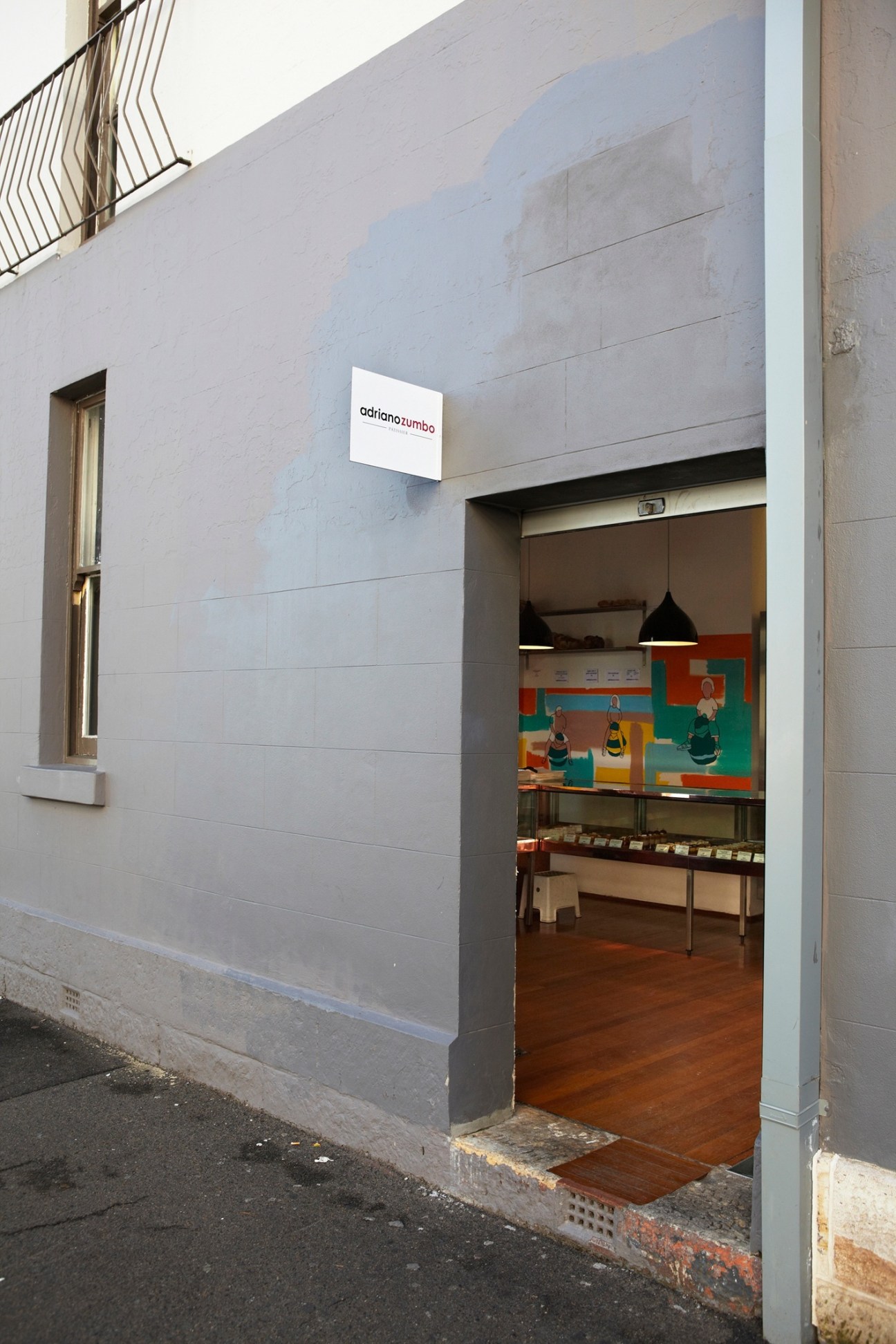 Exterior of Adriano Zumbo patisserie in Sydney with storefront signage and colorful mural visible inside.