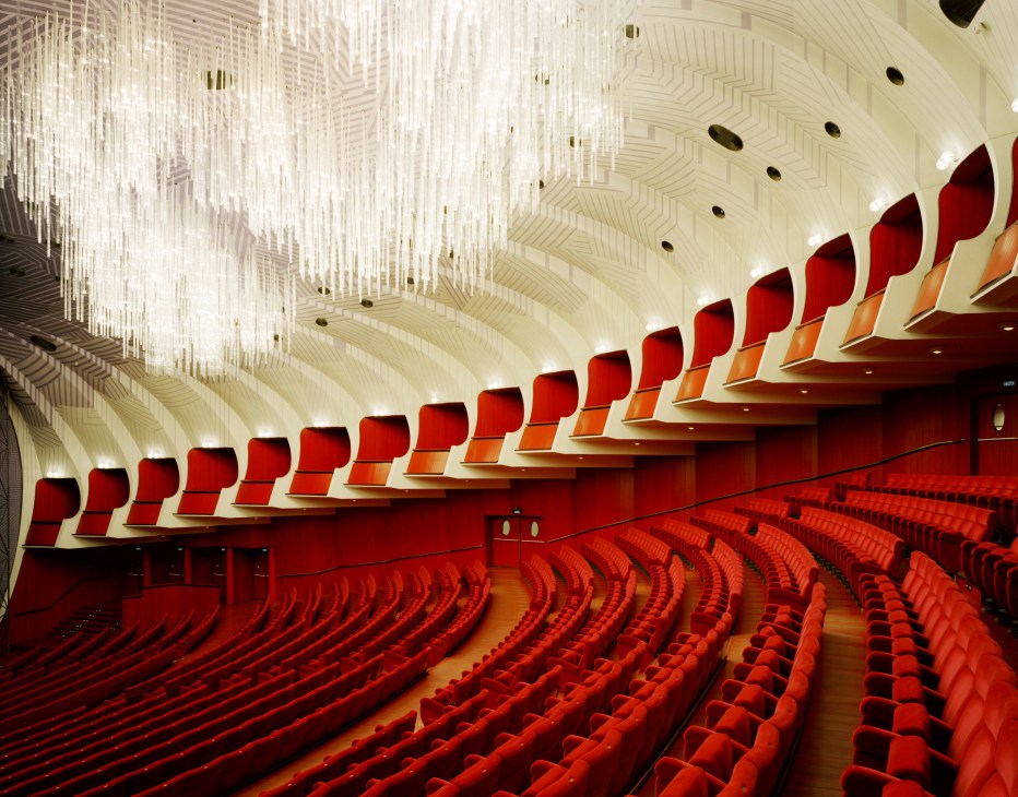 Teatro Regio auditorium with rows of red seats and an ornate cream and gold ceiling with chandelier.