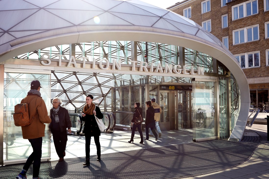 Commuters entering Triangeln station at Malmö City with modern glass and steel architecture.