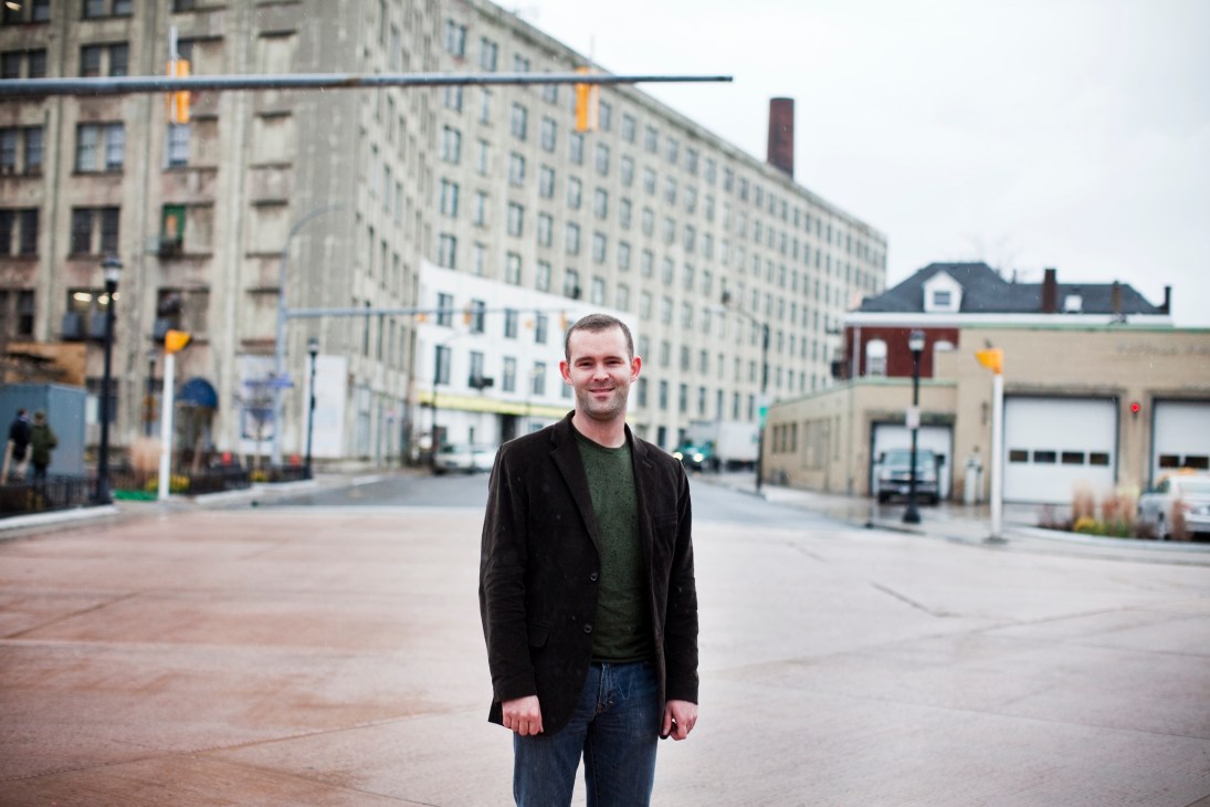 Urban planner Chris Hawley standing in a downtown Buffalo street surrounded by historic buildings.