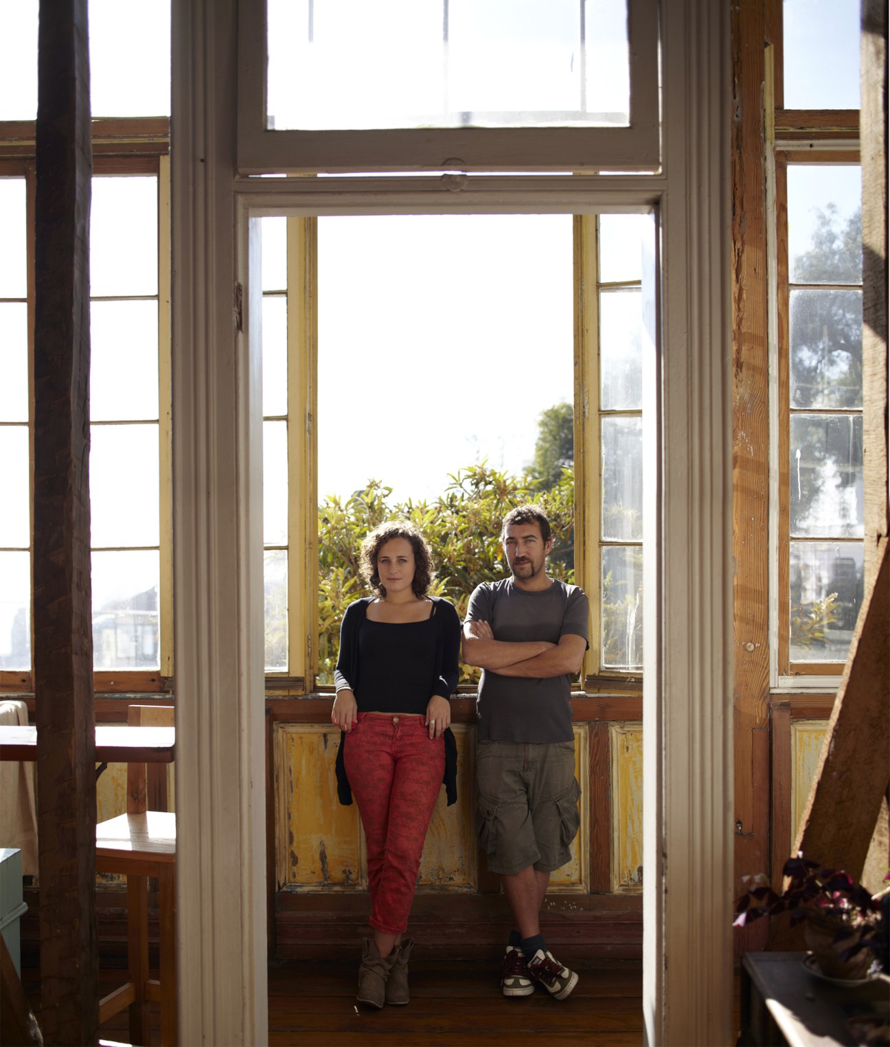 Caro Nelvi and Juan Pablo Guzman stand by large windows in a Victorian building overlooking Valparaíso.
