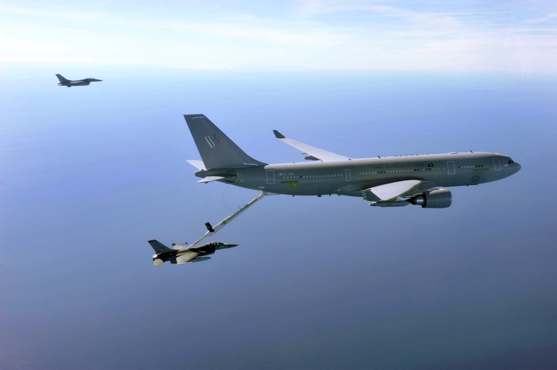 Military aerial refueling tanker aircraft with extended boom refueling a fighter jet in flight.