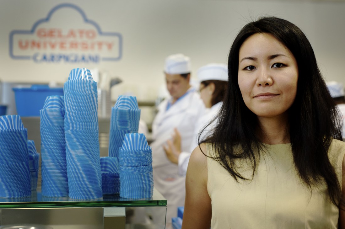 Kaori Ito, director of Carpigiani Gelato University, stands in the facility with blue serving cups and staff in the background.