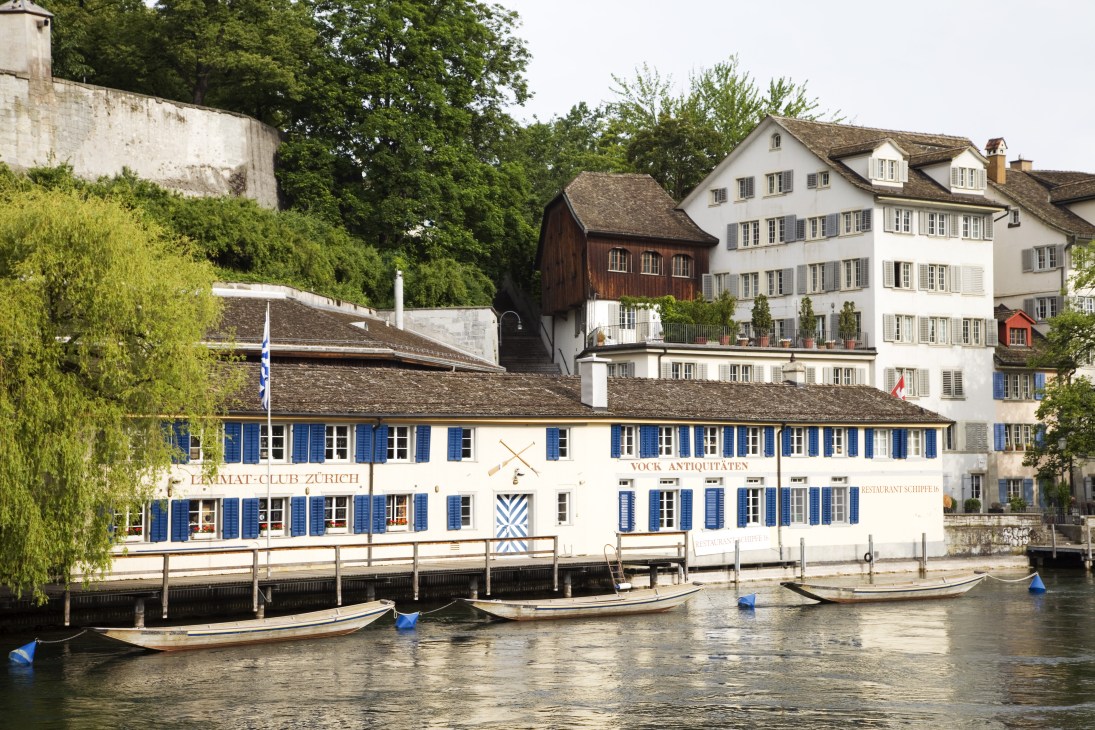 Zurich riverside buildings with blue shutters and boats moored in the water.