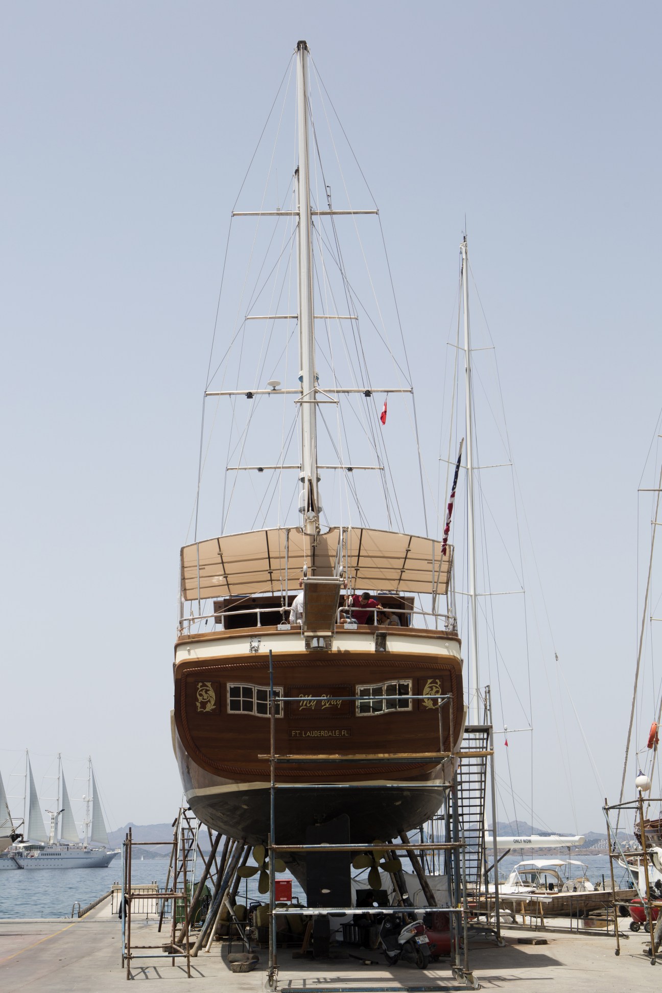 A wooden gulet vessel with twin masts in dry dock at Icmeler, Bodrum, showing the characteristic rounded stern and traditional construction.
