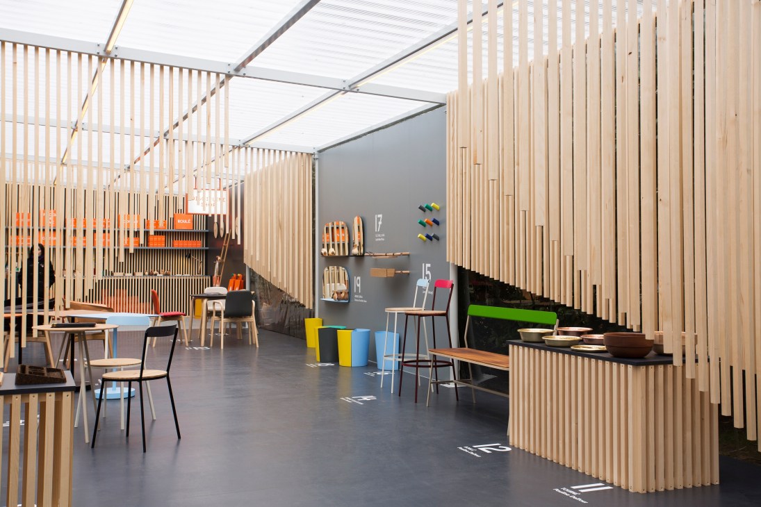 Interior of Discipline pop-up store with wooden slat partitions, modern chairs, and colorful design objects on display.