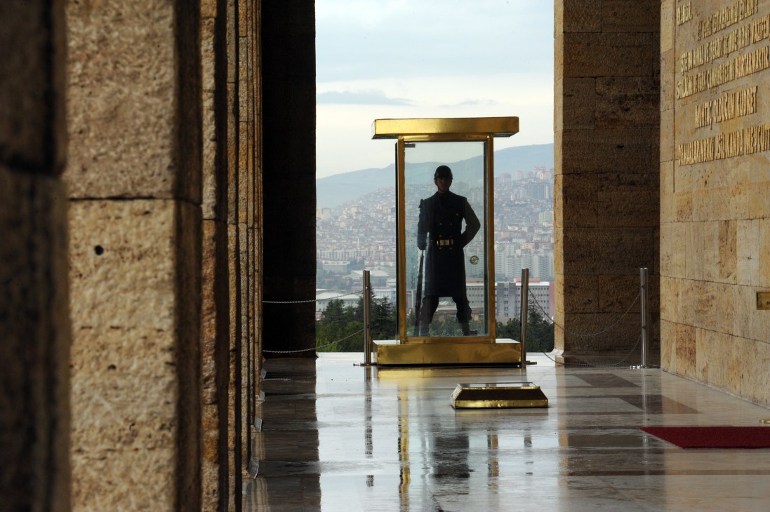 Soldier standing guard at Anitkabir mausoleum with Ankara cityscape visible in background.