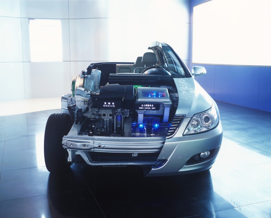 BYD hybrid car with hood open displaying engine components in showroom