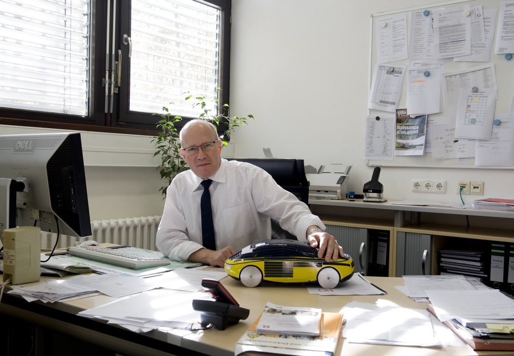 Professor Friedbert Pautzke in his office with a yellow solar-powered car model on his desk.