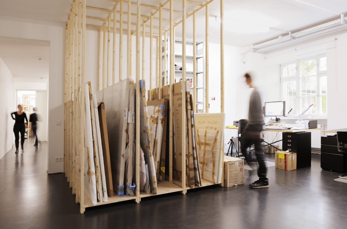 Interior of Sprüth Magers gallery storage with wooden shelving holding artworks and framed pieces.