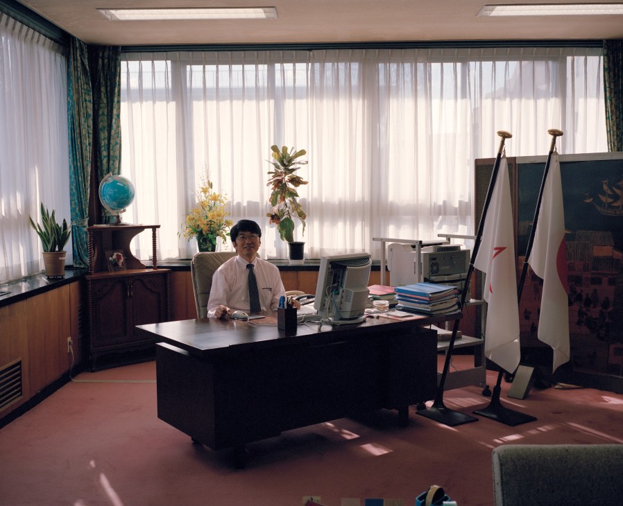 Tomihisa Taue, mayor of Nagasaki, seated at his desk in a bright office with large windows.
