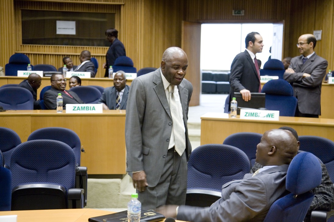 African diplomats in business attire sit at a conference table in the African Union headquarters chamber.