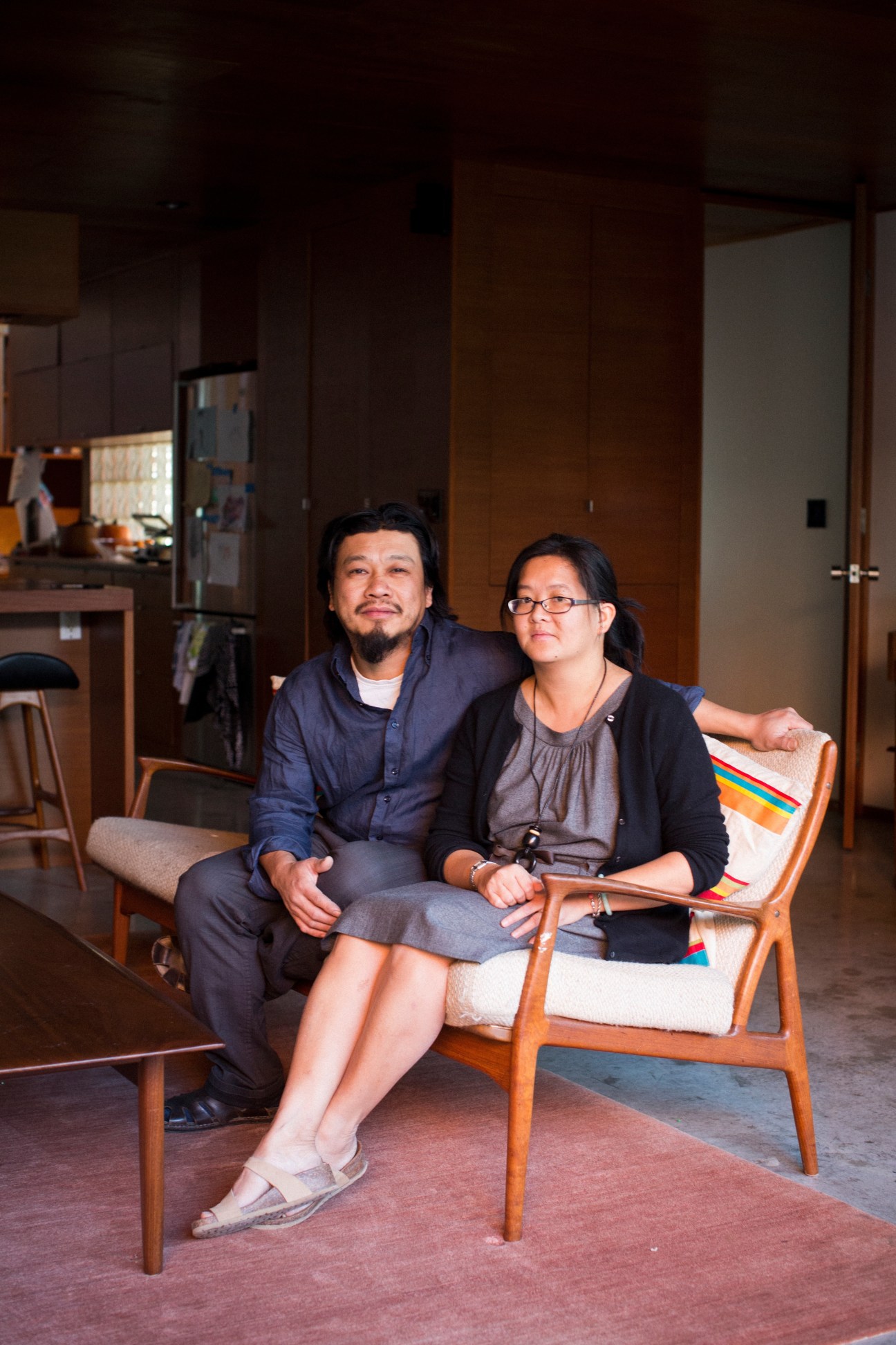 Architects Peter Tan and Christine Ho Ping Kong sitting on mid-century modern chairs in a minimalist interior space.
