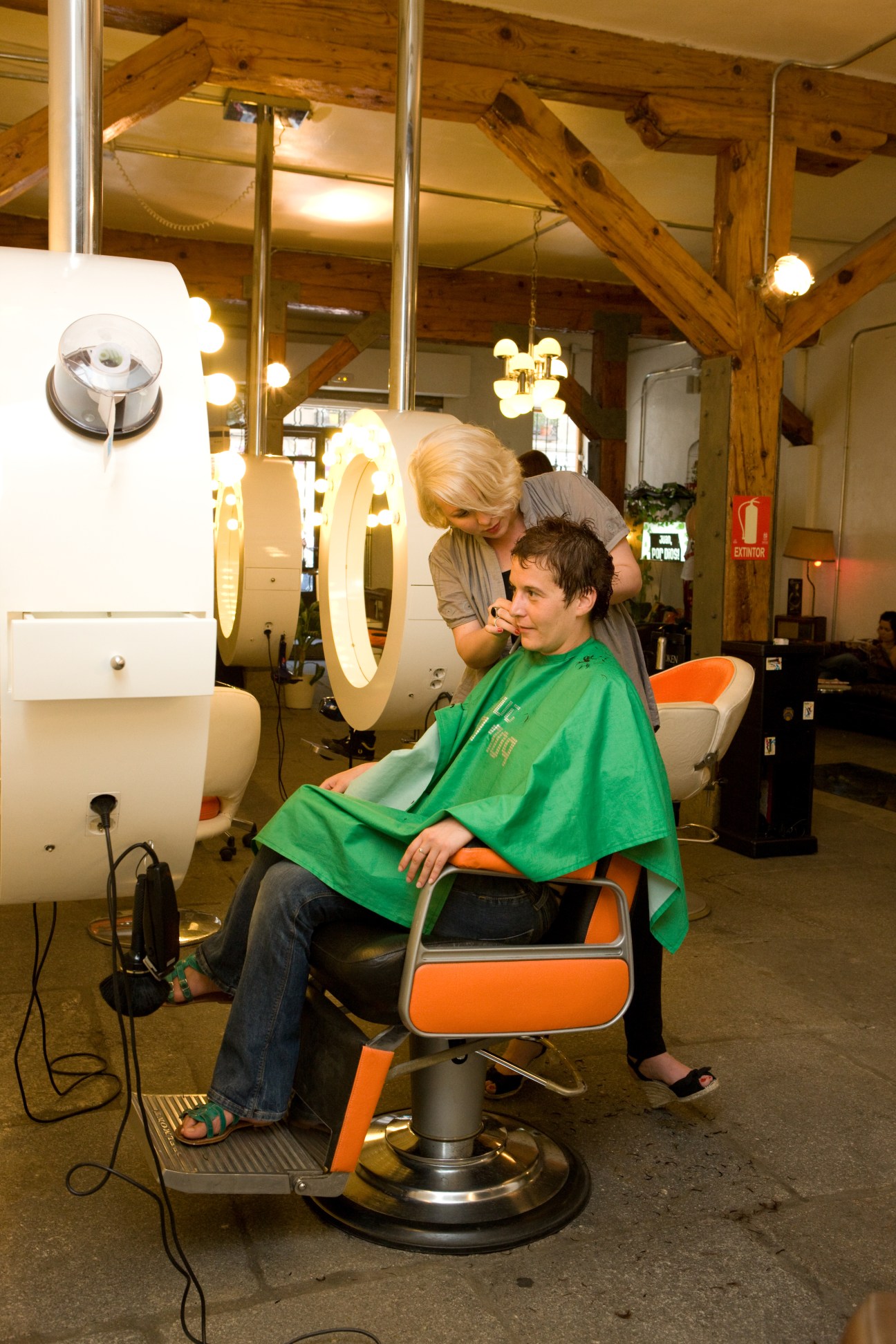 A hairdresser styles a young boy's hair in the Juan, por Dios! salon with exposed wooden beams.