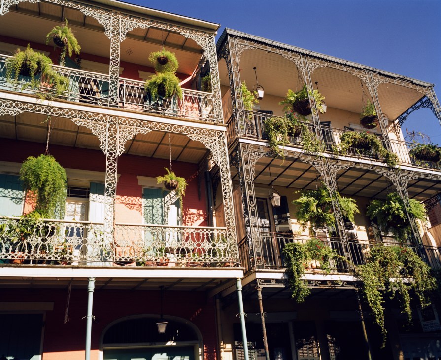 Historic New Orleans building with ornate cast-iron balconies and hanging plants.