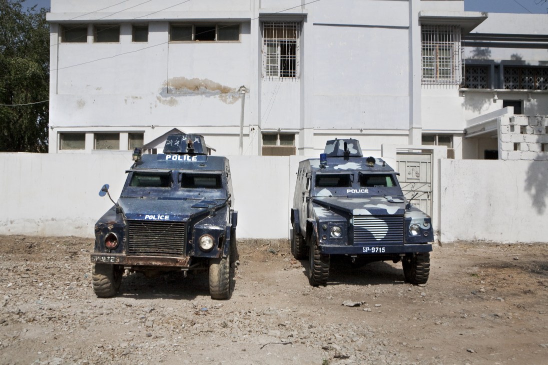Two blue armoured police vehicles parked in front of a white building in Karachi.