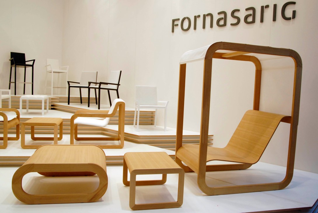 Fornasarig furniture showroom display with wooden chairs, benches, and sculptural pieces in light wood tones.